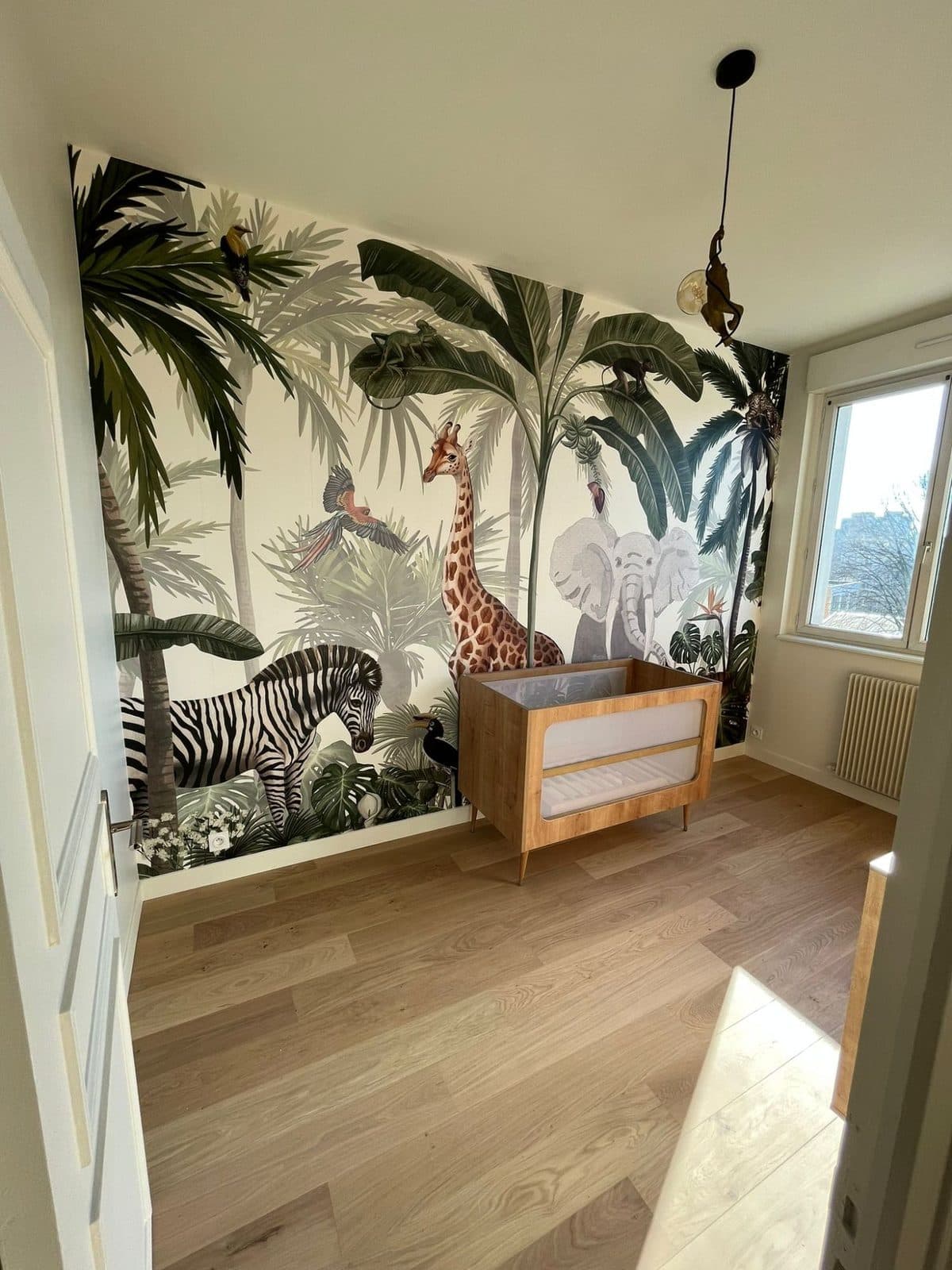 Chambre de bébé : papier peint panoramique jungle, lit en bois et parquet chêne clair