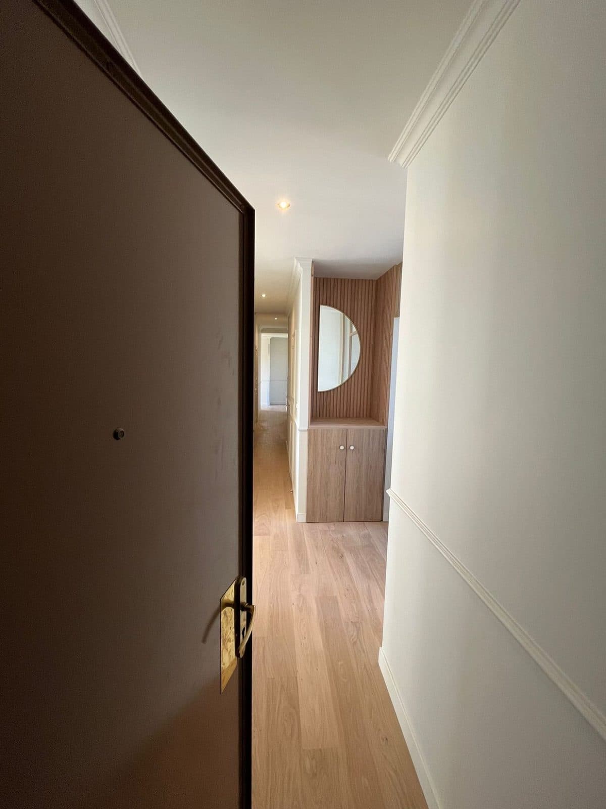Entrée : porte palière, couloir en parquet chêne, meuble à chaussures avec tasseaux bois et miroir rond