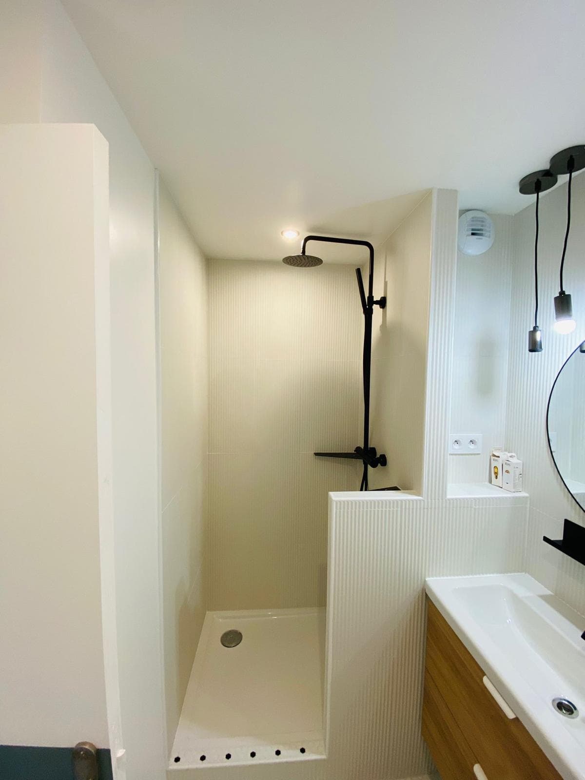 Douche avec faïence cannelée claire, colonne de douche noire et receveur blanc