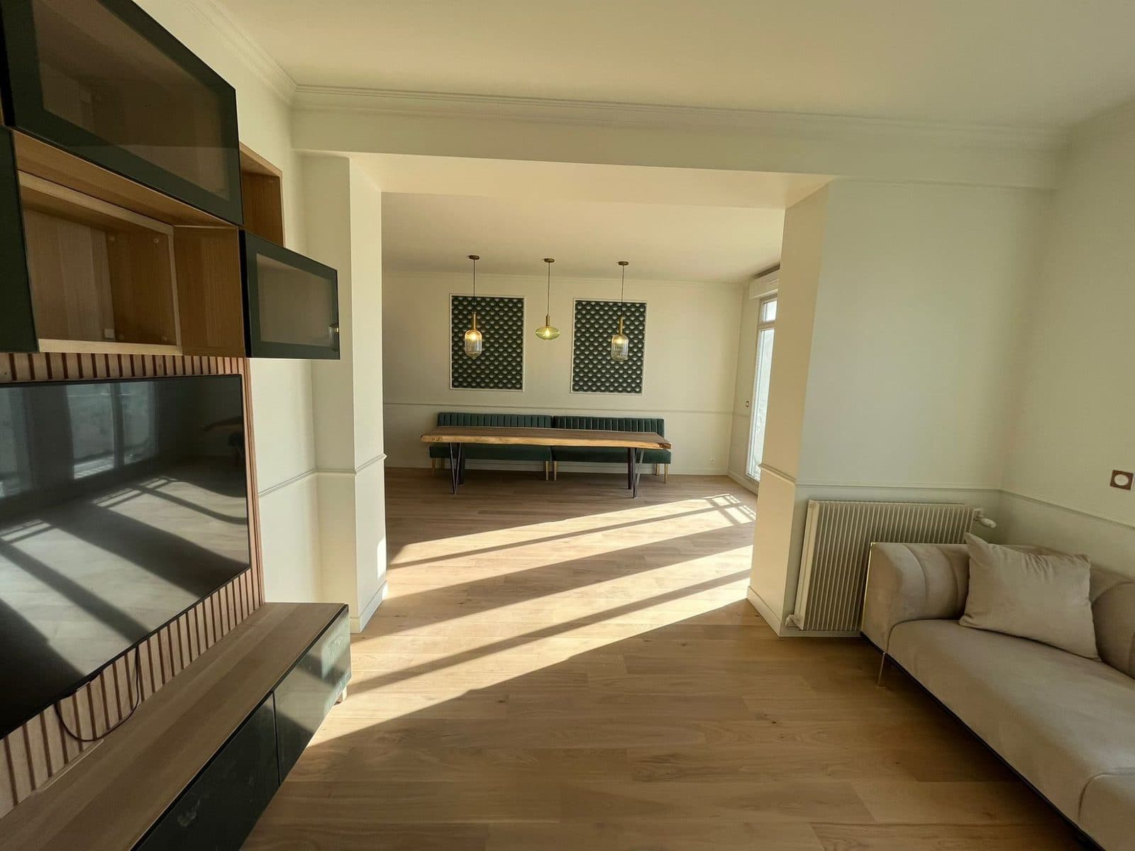 Salon ouvert sur la salle à manger : meuble TV en tasseaux, canapé beige, parquet chêne et moulures