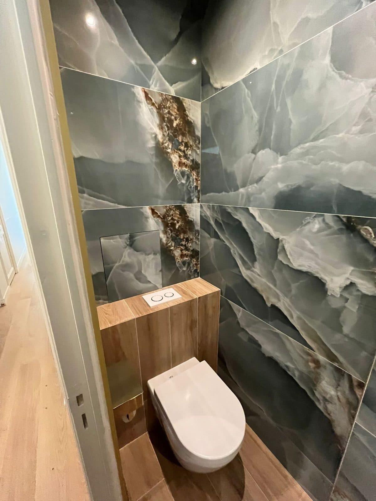WC suspendu : murs en grès effet onyx vert et coffrage habillé de carrelage effet bois